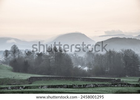 Beautiful layered landscape image of misty Spring morning in Lake District looking towards distant misty peaks