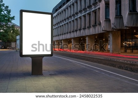 Street Billboard Mockup On Sidewalk At Night. Outdoor Advertising Lightbox with Car Light Trails In The Background