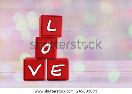 Love spelled in red wooden blocks on festive background