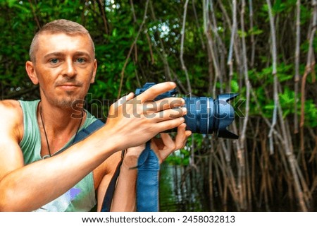 Young man male tourist with camera taking pictures on Boat safari trip through mangrove jungle forest in Bentota Ganga River Lake in Bentota Beach Sri Lanka.