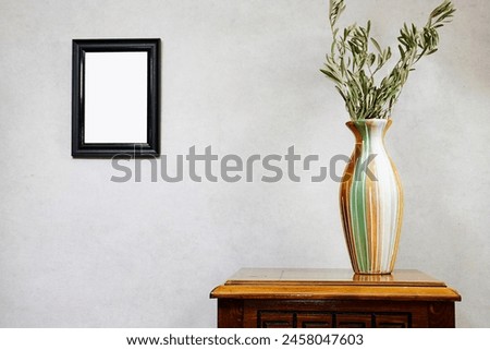 empty picture frame mockup and olives leaves vase on wooden table near grunge wall, autumn fall concept