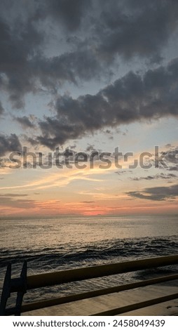 10 may 2023, The image depicts a serene beach with a body of water under a sky filled with clouds. The scene captures a peaceful and calming atmosphere of nature during sunset.