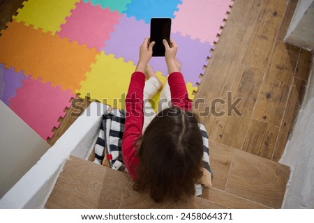 View from above of little kid's hands holding smart mobile phone with blank black empty digital touch screen. Mockup. Copy space for mobile application or advertising text. People. Wireless technology