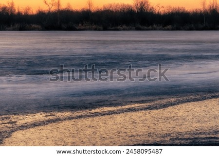 North-eastern European river after frosty winter. Porous ice began to melt, river is swollen, state of ice week before ice break (ice-boom). Aurora, sunrise colors on a spring moning Royalty-Free Stock Photo #2458095487