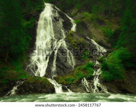 Waterfall Schleierwasserfall in the Osttirol region on a summer rainy day. Lush green vegetation.  Alps, Austria.  Royalty-Free Stock Photo #2458117767