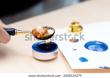 Hand with a melting spoon dissolving multicolored sealing wax