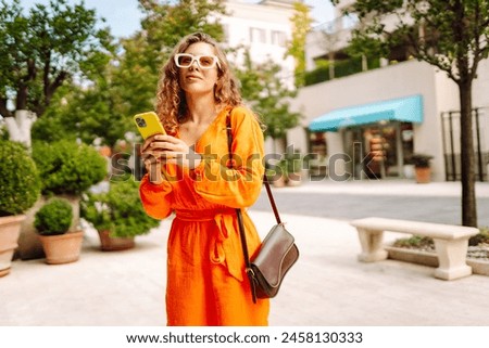 Woman traveler with a mobile phone. Happy Woman texting, browsing, using her smartphone on a warm sunny day. Positive emotions. Apps.