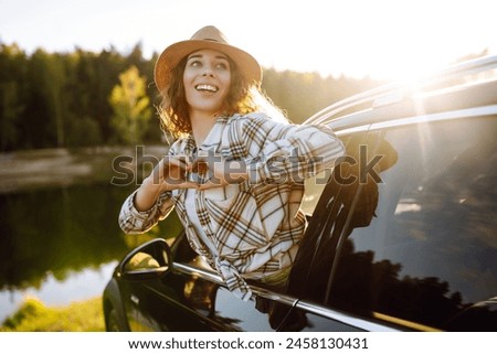 Relaxed woman leaning out car window during summer trip.  Lifestyle, travel, tourism, nature, active life.