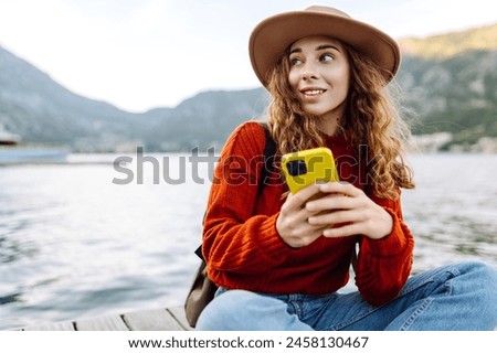 Young woman with phone on the embankment. Tourist during holidays. Lifestyle, travel, nature, active life.