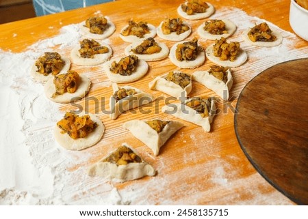 Sweet gomentashi cookies fashioned on a table next to flour and menorah. Horizontal photo