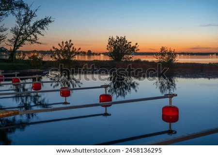 Empty marina on the lake after sunset, red buoys Royalty-Free Stock Photo #2458136295