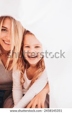 A close up picture of a mother and her little toddler daughter smiling or laughing to the camera