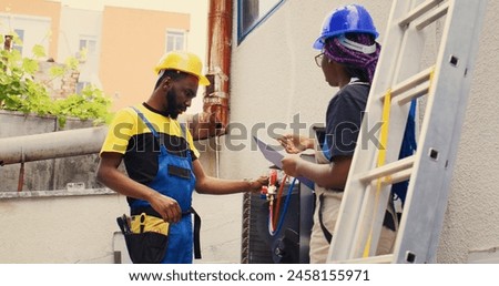 Diverse team of precise engineers brainstorming possible ways to recondition damaged outdoor hvac system. Adept repairmen coworkers commissioned to repair broken air conditioner Royalty-Free Stock Photo #2458155971
