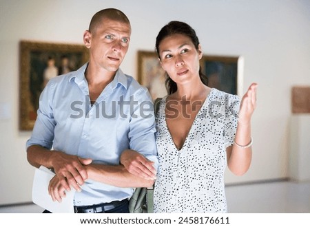 Woman and man walking in picture gallery and looking at exposition