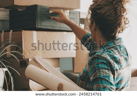 One alone woman working at home with cardboard carton box after relocating new home. Indoor leisure activity at home. Mortgage new beginnings adventure. Independence lifestyle lady. Moving apartment Royalty-Free Stock Photo #2458214761