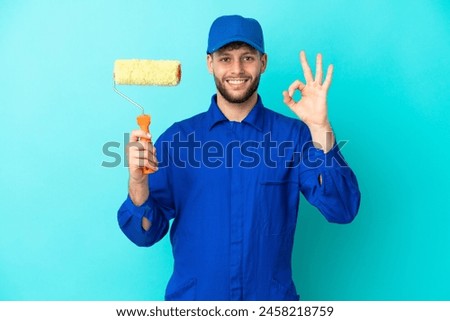 Painter caucasian man isolated on blue background showing ok sign with fingers