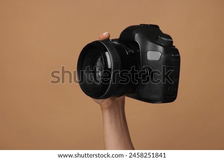 Photographer with camera on brown background, closeup. Space for text