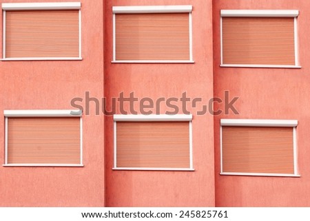 Red Building Facade with Six Closed Windows Shutters Background with Space for Text or Image