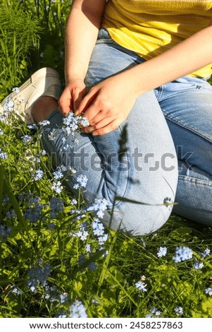 A girl collects flowers for a herbarium in a meadow Royalty-Free Stock Photo #2458257863
