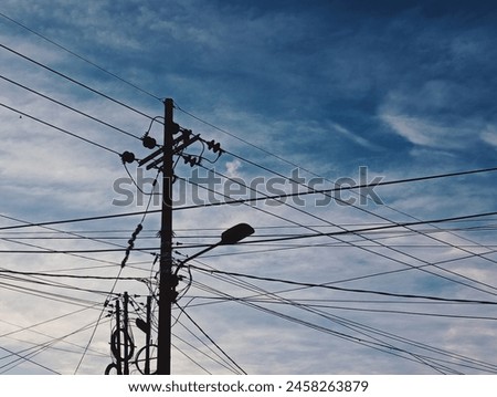Silhouettes of cable pole and many tinged cables Royalty-Free Stock Photo #2458263879