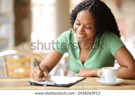 Happy black woman filling form in a restaurant terrace