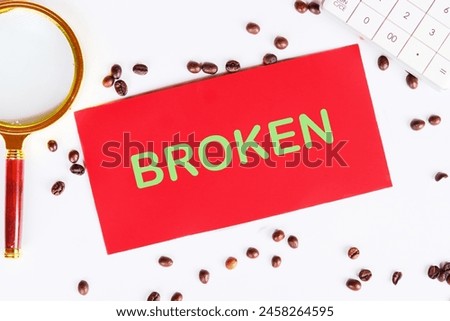 A word Broken on red paper on a white background with coffee beans and a magnifying glass