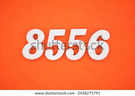 The number 8556 is made from white painted wood placed on a background of orange paper.