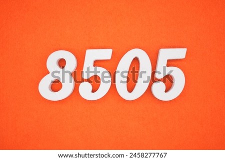 The number 8505 is made from white painted wood placed on a background of orange paper.