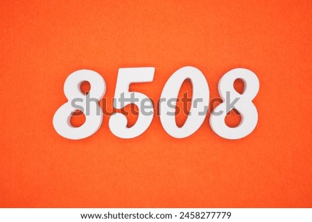 The number 8508 is made from white painted wood placed on a background of orange paper.