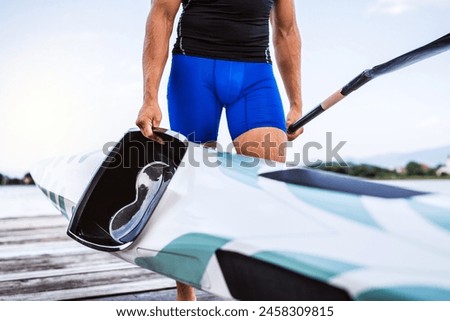 Young canoeist carry canoe and paddle, going on water. Concept of canoeing as dynamic and adventurous sport. Royalty-Free Stock Photo #2458309815