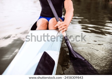 Close up of canoeist sitting in canoe holding paddle, in water. Concept of canoeing as dynamic and adventurous sport. Royalty-Free Stock Photo #2458309843