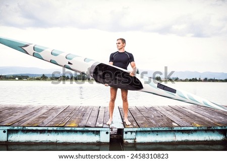 Young canoeist holding canoe and paddle, going into water, wstanding on wooden dock. Concept of canoeing as dynamic and adventurous sport Royalty-Free Stock Photo #2458310823