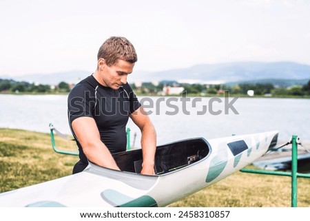 Young canoeist preparing canoe and paddle, going on water. Concept of canoeing as dynamic and adventurous sport. Royalty-Free Stock Photo #2458310857