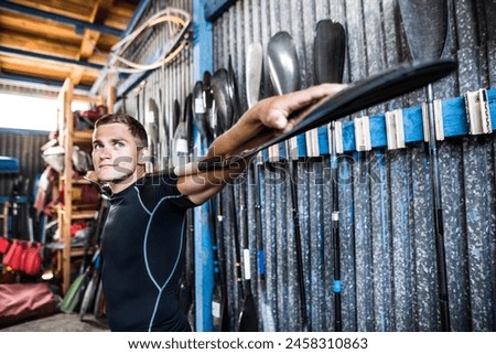 Young canoeist holding paddle behind his head, on shoulders. Concept of canoeing as dynamic and adventurous sport. Royalty-Free Stock Photo #2458310863