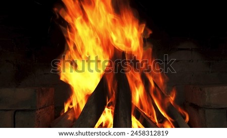 The roaring fire in the fireplace, with its unique orange hues, contrasts against the dark brick wall, creating a cozy atmosphere. Royalty-Free Stock Photo #2458312819