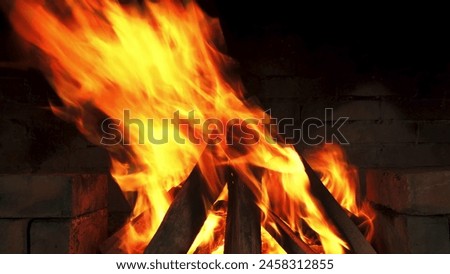 The fire's orange glow dances against the brick wall, creating a warm and cozy atmosphere. Royalty-Free Stock Photo #2458312855