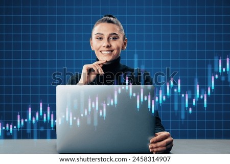 Happy young european woman sitting at desk with laptop and creative growing candlestick forex chart on blue grid background. Financial growth and stock concept