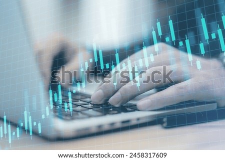 Close up of male hands using laptop on desk with creative growing candlestick forex chart on blue grid background. Financial growth and stock concept. Double exposure