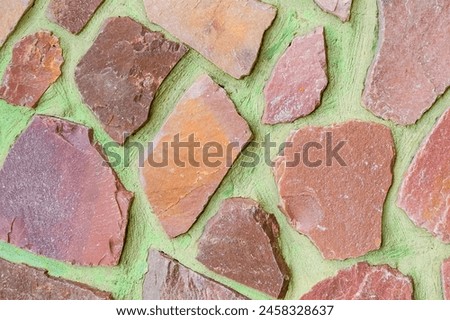 It is photo of colorful stones on green background. Its close up of multicolored stone wall of building. It is photo of mosaic tile floor. It's the view of wall texture.
