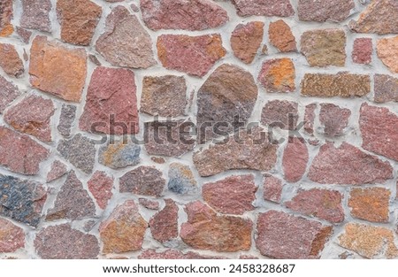 It's close up view of colorful wall. Its the photo of multicolor stonewall. It is photo of multicolored srone wall. its view of red sidewalk. It's view of mosaic stonewall