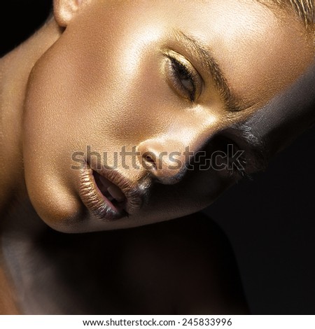  Girl with gold and silver skin in the image of an Oscar. Art image beauty face. Picture taken in the studio on a black background.
