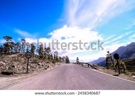 A road with a sign that says No Entry and a No Parking sign. The road is empty and there are no cars or people on it. The sky is clear and the sun is shining, real image