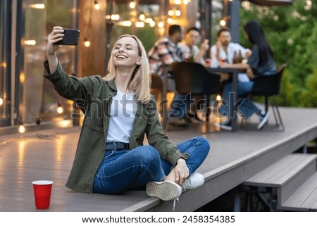 Woman making selfie with group of friends spending time making picnic