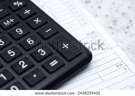 A closeup of a calculator, a peripheral input device, on top of a sheet of paper, office equipment often used with a computer keyboard or personal computer for calculations Royalty-Free Stock Photo #2458359435