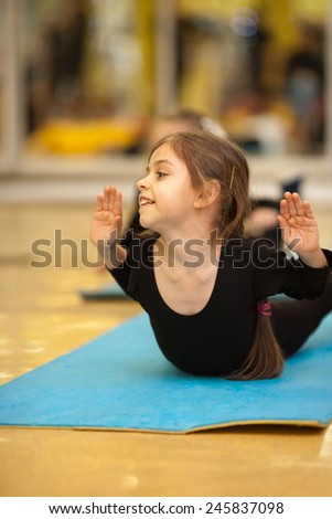 Little girl making exercises on floor mat in bodysuit