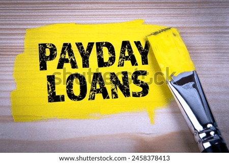 PAYDAY LOANS. Yellow paint and paint brush on wooden texture background.