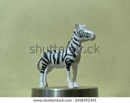 Realistic toy zebra made of plastic isolate on jar lid stainless with,yellow background

