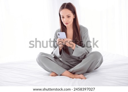 Photo of shiny positive lady grey sleepwear typing messages apple samsung iphone gadget indoors home bedroom