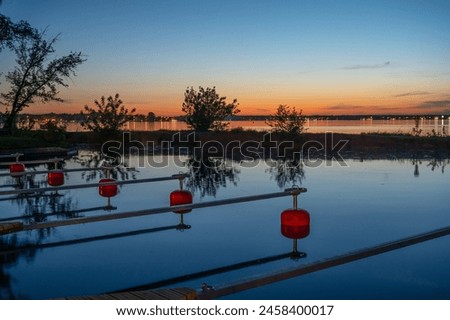 Empty marina on the lake after sunset, red buoys Royalty-Free Stock Photo #2458400017