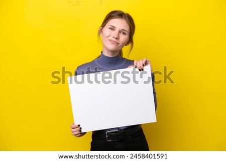 Young English woman isolated on yellow background holding an empty placard with happy expression